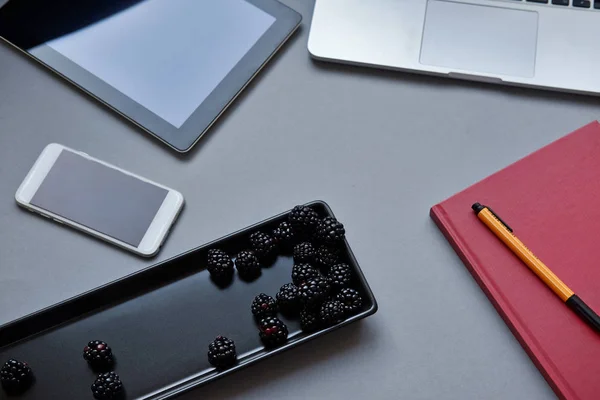 Fresh berries, healthy lunch in the office. Laptop, tablet, smartphone and notebook on a table — Stock Photo, Image