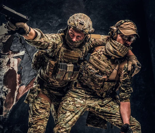 Conflicto de combate, misión especial. El soldado militar llevando a su compañero de equipo fuera del campo de batalla. Foto del estudio contra una pared oscura —  Fotos de Stock