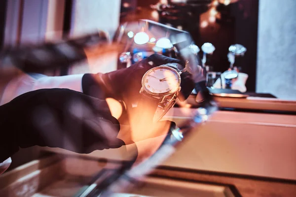 Close-up of the sellers hands in gloves shows the exclusive mens watch from the new collection — Stock Photo, Image