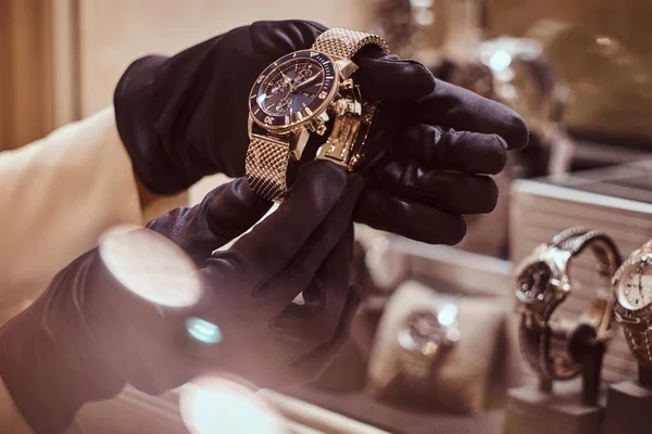 Close-up of the sellers hands in gloves shows the exclusive mens watch from the new collection — Stock Photo, Image