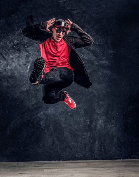 Emotional stylish dressed guy performing break dance jumping.