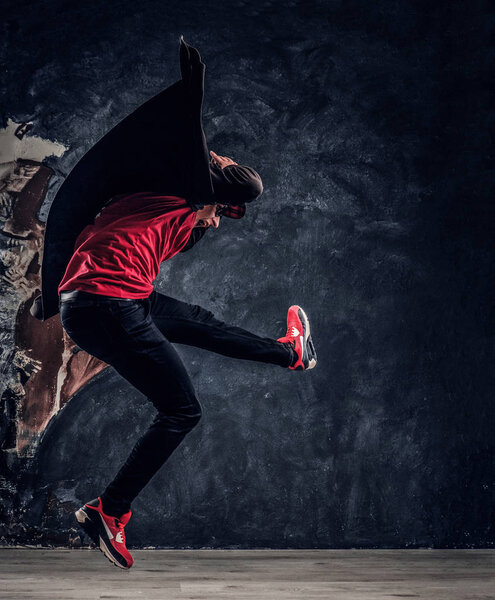 Emotional stylish dressed guy performing break dance jumping.