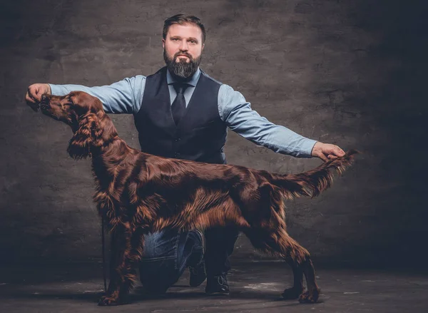 Caçador de meia-idade vestido com roupas elegantes se senta em seu joelho e mostra o comprimento total de seu Setter Inglês puro . — Fotografia de Stock