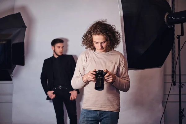 Fotógrafo novato en una sesión de fotos en un estudio con un chico elegante — Foto de Stock