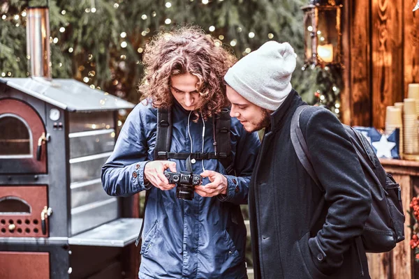 Two friends strolling through the Christmas fair with a camera — Stock Photo, Image