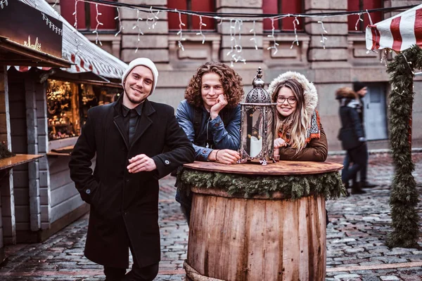 Jonge toeristen glimlachen en kijken een camera terwijl u ontspant met een drankje op de markt van het stadsplein — Stockfoto