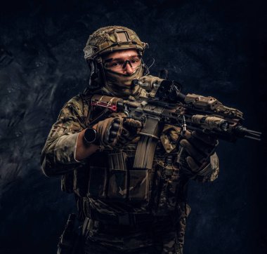 Elit birimi, Özel Kuvvetler asker bir saldırı tüfeği bir lazer görme ve amaçlar ile hedef kamuflaj üniformalı. Karanlık bir duvara Studio fotoğraf  
