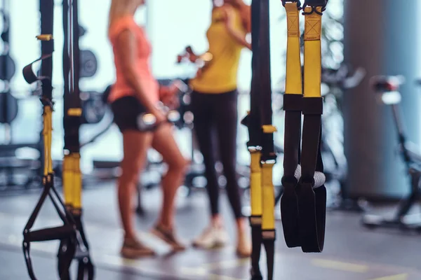 Sport Vering bandjes in de voorgrond en twee meisjes van de fitness op de achtergrond in de moderne sportschool. — Stockfoto