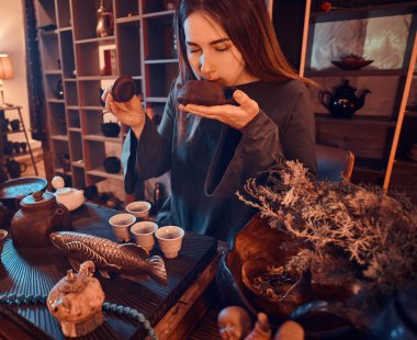 Çin çay töreni. Oryantal usta bir gri giyen bir çaydanlık tutan elbise ve ahşap iç karanlık odada taze doğal çay kokusu nefes.