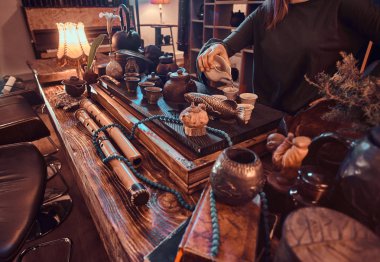 Oryantal usta bir gri giyen bir ahşap iç ile karanlık odada bir bardağa dökme doğal çay elbise. Gelenek, sağlık, uyum.