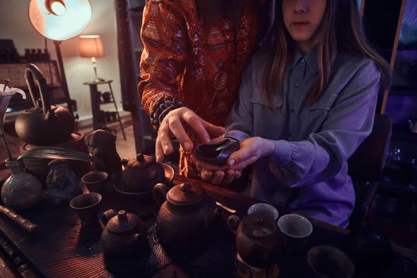 Cérémonie du thé chinois. Maître de thé en kimono avec une fille lors d'une cérémonie du thé chinois dans la pièce sombre avec un intérieur en bois . — Photo