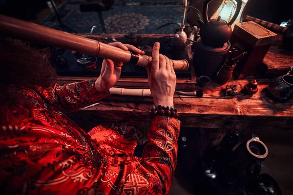 Tradition, santé, harmonie. Cérémonie du thé chinois. Maître de thé en kimono se produit dans la pièce sombre avec un intérieur en bois, jouer sur une flûte de bambou — Photo