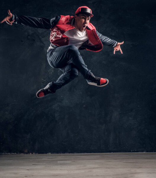 Emotional stylish dressed guy performing break dance jumping.