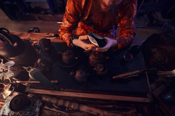 Mestre caucasiano em quimono fazendo chá natural no quarto escuro com um interior de madeira. Tradição, saúde, harmonia. Cerimônia de chá chinês — Fotografia de Stock