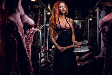 Fitness kadın iç çamaşırı ve et karkas ortasında buzdolabında bir depoda balta ile poz önlük