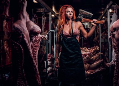 Fitness kadın iç çamaşırı ve et karkas ortasında buzdolabında bir depoda balta ile poz önlük