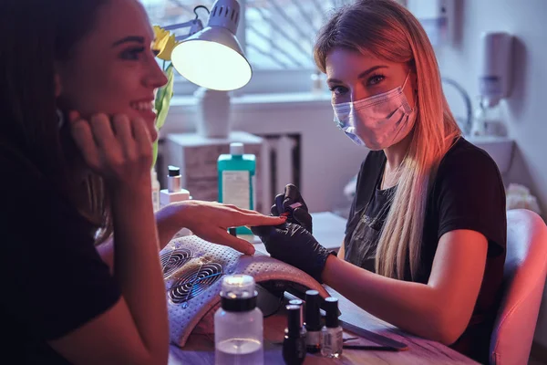 Szczęśliwa młoda kobieta odbiera manicure przez mistrza kosmetyczka w salonie piękności. — Zdjęcie stockowe