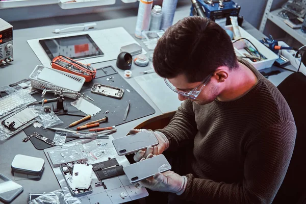 Técnico tiene dos teléfonos inteligentes idénticos para la comparación, en una mano rota y en otro nuevo —  Fotos de Stock