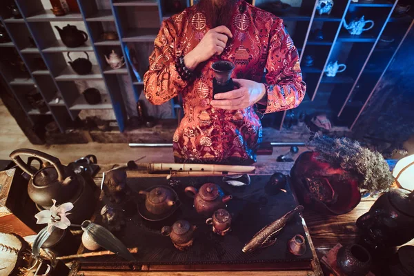 Maître caucasien en kimono faisant du thé naturel dans la pièce sombre avec un intérieur en bois. Tradition, santé, harmonie. Cérémonie du thé chinois — Photo