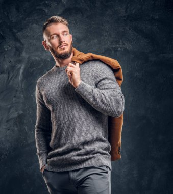 Mens güzellik, mevsimlik moda. Şık erkek demi-sezon kat bir omuz ile poz. Studio fotoğraf bir karanlık duvar arka plan