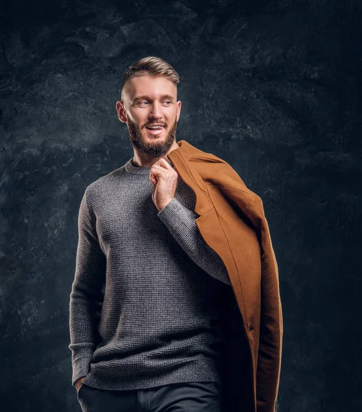 Beleza masculina, moda sazonal. Retrato de um homem elegante segurando sua demi-temporada casaco. Foto do estúdio contra um fundo de parede escura — Fotografia de Stock