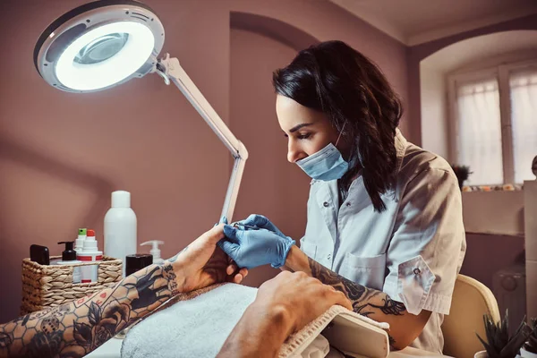 Człowiek z tatuażem na ręku otrzymujących manicure przez kosmetyczkę w salonie piękności. Wirydarz-do góry ręce — Zdjęcie stockowe