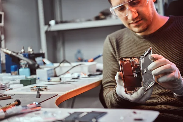 Elektroniker zeigt ein Smartphone mit kaputtem Körper in einer Werkstatt — Stockfoto