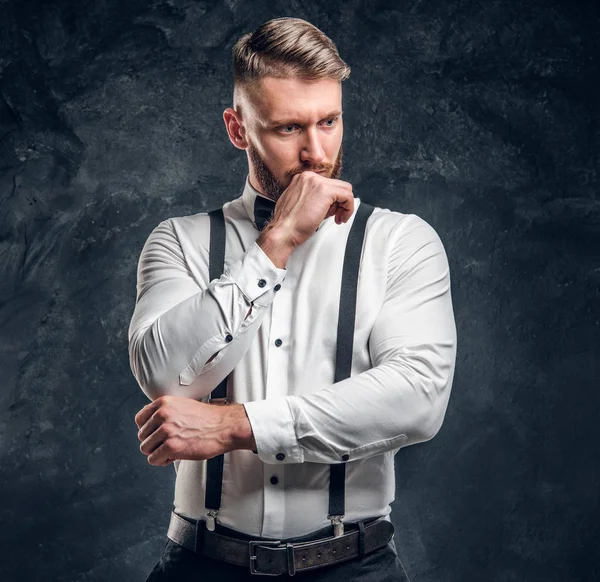 Homme pensif penser à quelque chose d'important. Jeune homme élégamment habillé en chemise avec nœud papillon et bretelles posant avec la main sur le menton . — Photo