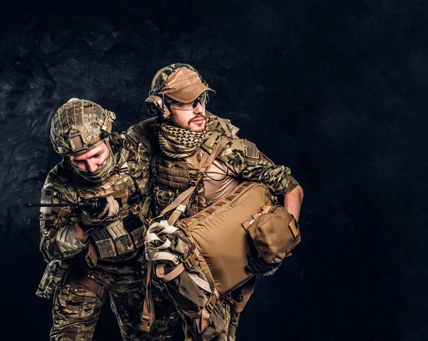 Conflicto de combate, misión especial, retirada. Médico militar rescata a su compañero herido llevándolo fuera del campo de batalla . —  Fotos de Stock