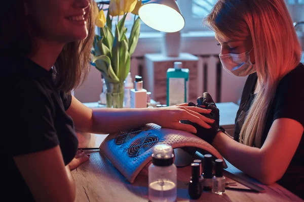 Happy young woman receiving a manicure by a beautician master in the beauty salon. — Stock Photo, Image