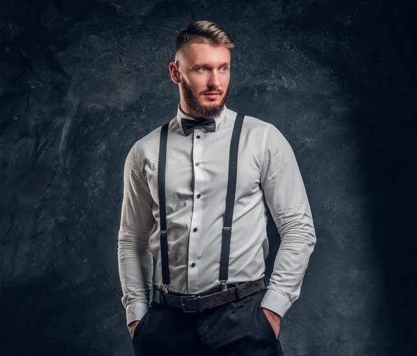 Κομψά ντυμένοι νεαρός άνδρας με πουκάμισο με παπιγιόν και ζαρτιέρες. Στούντιο φωτογραφία τοίχο σκούρο φόντο — Φωτογραφία Αρχείου