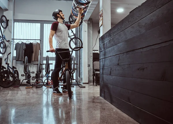 Jeune homme dans un casque de protection et de choisir un pneu de vélo pour son vélo dans la boutique — Photo