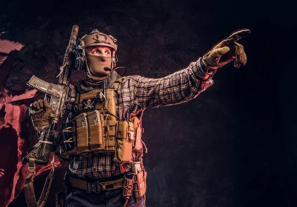 Forças especiais soldado em uniforme de camuflagem posando com rifle de assalto, olha para o lado e aponta para o alvo . — Fotografia de Stock