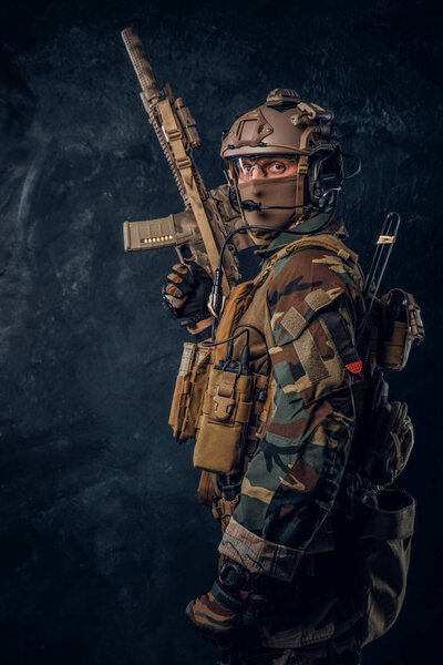 Elite unit, special forces soldier in camouflage uniform posing with assault rifle.