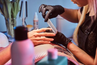 Manikür ustası müşterileri çivi ile çalışıyor. 