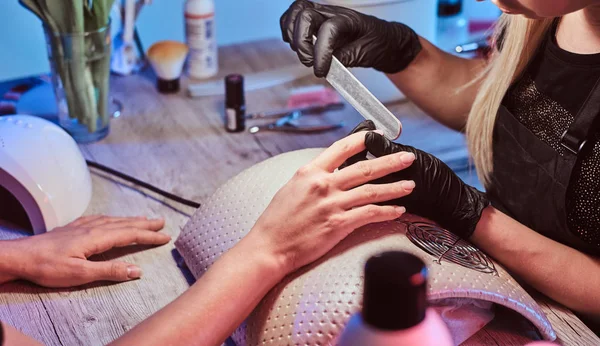 Manikür ustası müşterileri çivi ile çalışıyor. 