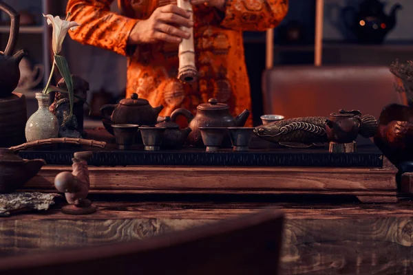 Tradition, santé, harmonie. Cérémonie du thé chinois. Maître de thé en kimono se produit dans la pièce sombre avec un intérieur en bois, jouer sur une flûte de bambou — Photo