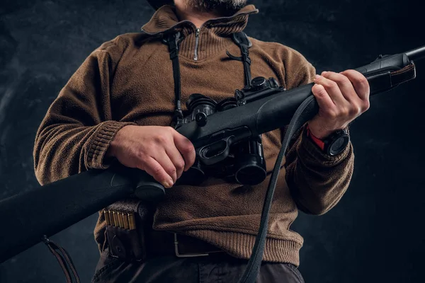 Close up view on a hands with rifle. Studio photo of a hunter against dark wall background — Stock Photo, Image