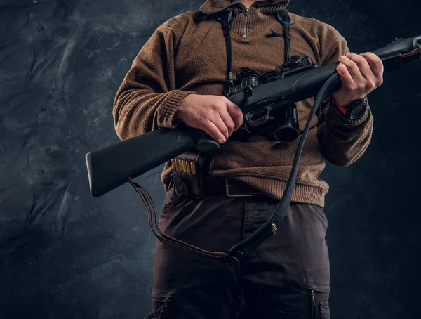 Close up view on a hands with rifle. Studio photo of a hunter against dark wall background — Stock Photo, Image