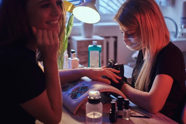 Happy young woman receiving a manicure by a beautician master in the beauty salon. — Stock Photo, Image