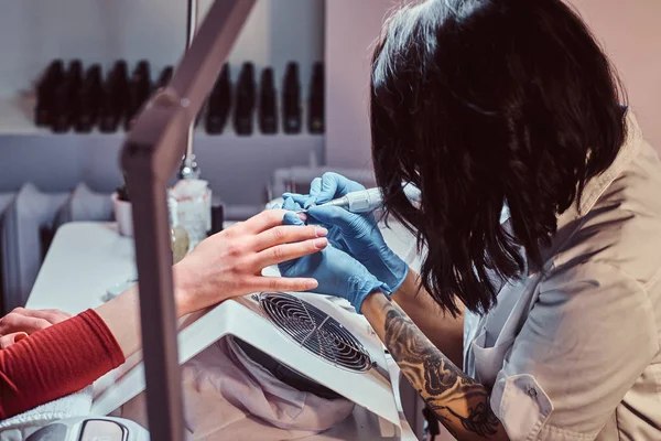 Mestre esteticista em luvas aplicando broca de unhas para aparar e remover cutículas. Manicura de hardware em um salão de beleza — Fotografia de Stock