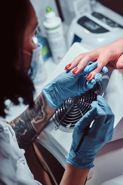 Kosmetikerin, die einer Kundin lange durchsichtige künstliche Nägel macht. Maniküre im Schönheitssalon — Stockfoto