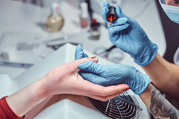 Esteticista fazendo longas unhas artificiais transparentes para um cliente feminino. Procedimento de manicura em um salão de beleza — Fotografia de Stock
