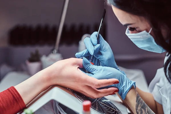 Beautician working with a client in a beauty salon, applying color nail polish. — Stock Photo, Image