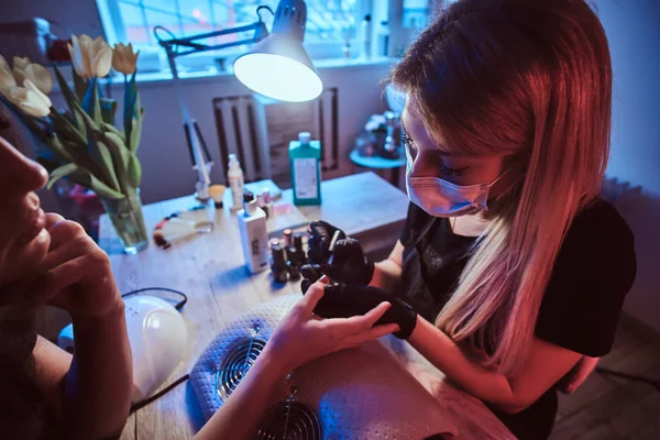 Bonito mestre manicure está trabalhando em clientes unhas . — Fotografia de Stock