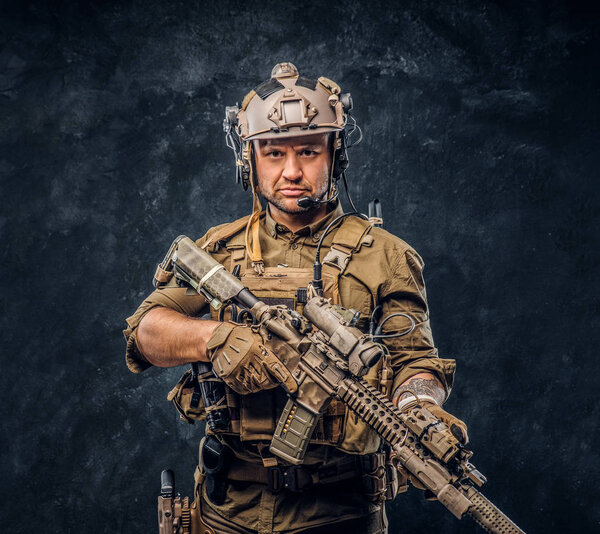 Elite unit, special forces soldier in camouflage uniform posing with assault rifle.