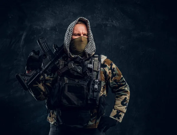 Forças especiais soldado em uniforme militar usando máscara e capuz posando com um rifle de assalto . — Fotografia de Stock