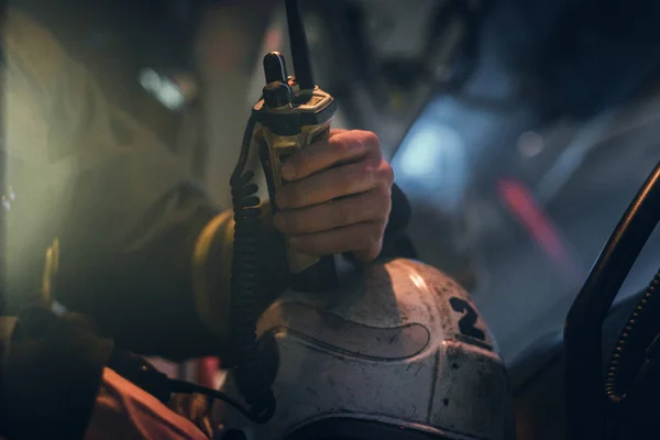 Bombeiro com um uniforme de protecção sentado no camião dos bombeiros e a segurar walkie-talkie. Mão para cima . — Fotografia de Stock