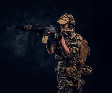 Elit birimi, Özel Kuvvetler asker bir saldırı tüfeği bir lazer görme ve amaçlar ile hedef kamuflaj üniformalı. Karanlık bir duvara Studio fotoğraf  