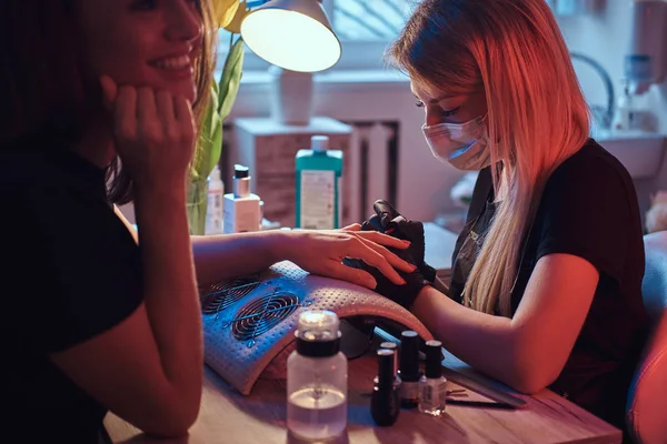 Feliz joven recibiendo una manicura por un maestro esteticista en el salón de belleza . —  Fotos de Stock